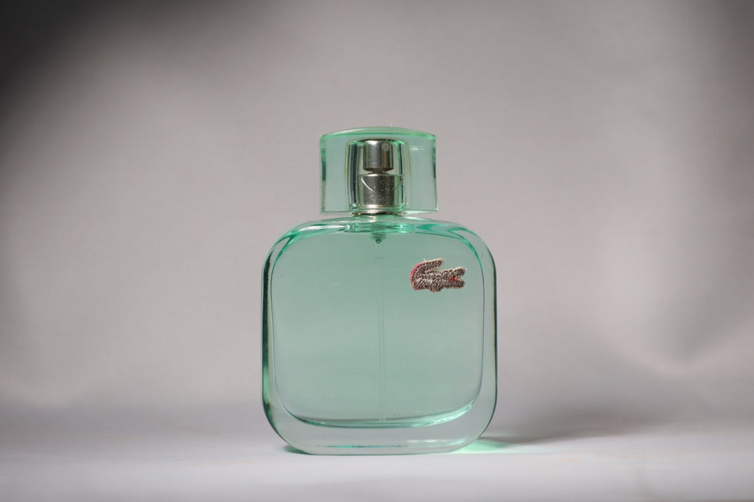 Here is a short caption: lacoste eau de toilette fragrance bottle is featured.